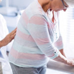 Physiotherapist giving back massage to senior patient